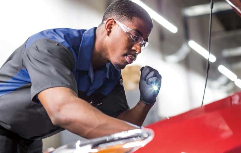 service technician looks at Subaru engine