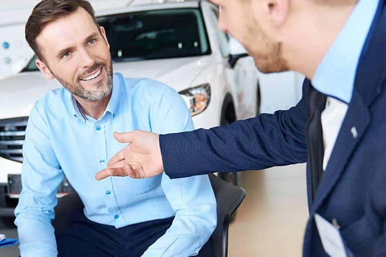 smiling man meets finance officer car showroom