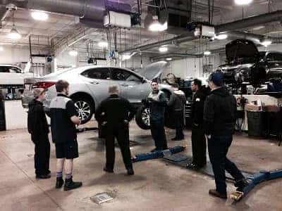 Acura of Orange Park Service Technicians by a raised car