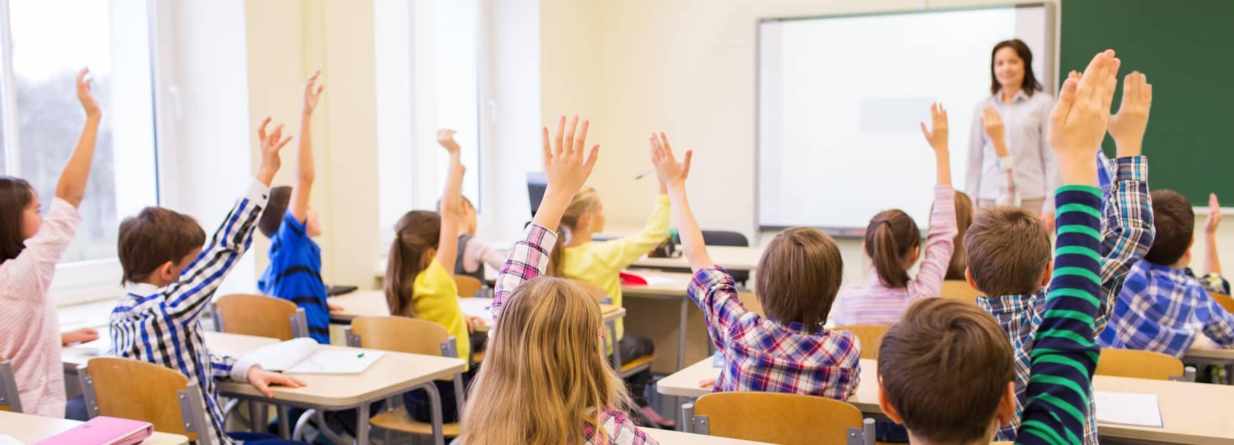 children raise hands classroom