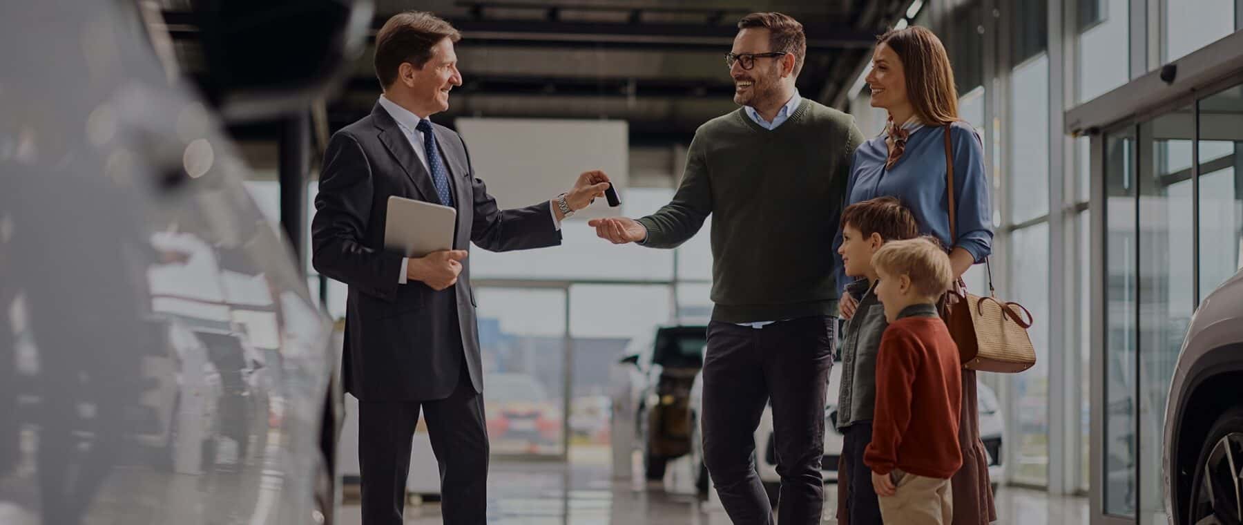 Family getting vehicle keys from a dealer