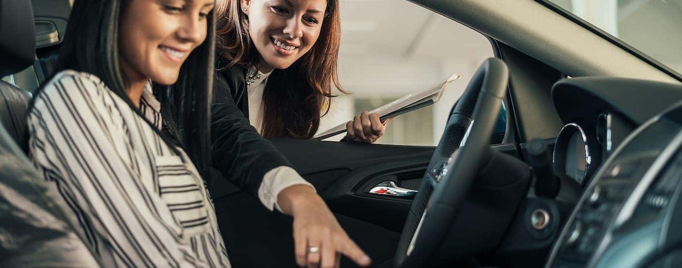 Vehicle saleswoman showing the features of a vehicle and its interior to a prospective female buyer