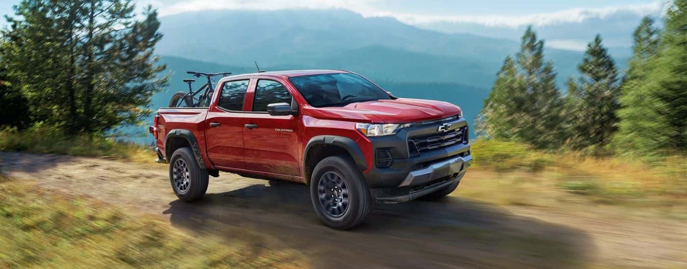 A red 2024 Chevy Colorado Trail Boss is shown driving off-road.