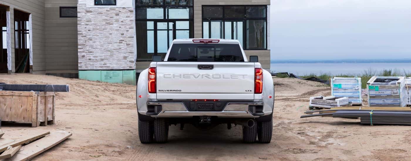 A white 2024 Chevy Silverado 3500 HD for sale is parked at a construction site.