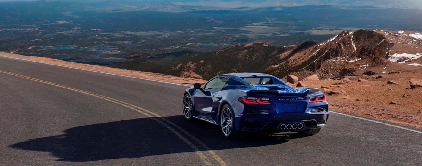 A blue 2025 Chevy Corvette ZR1 is shown from the rear on a mountain road.