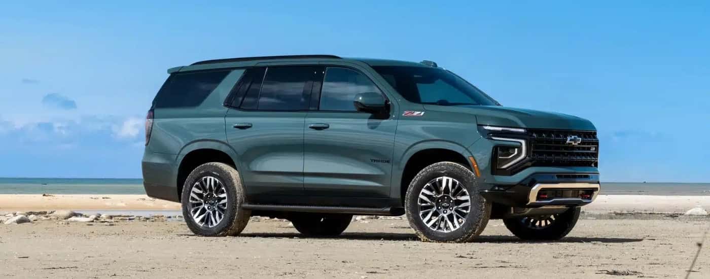 A green 2025 Chevy Tahoe Z71 is shown parked on a beach.