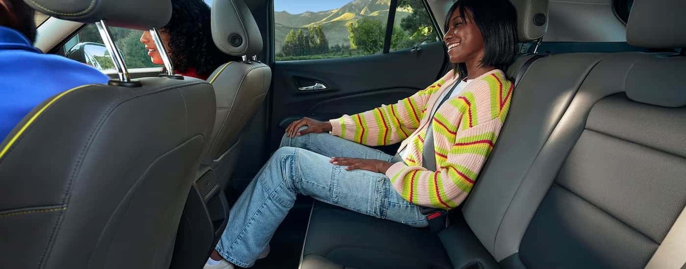 A woman is sitting in the back seat of a 2024 Chevy Trax.