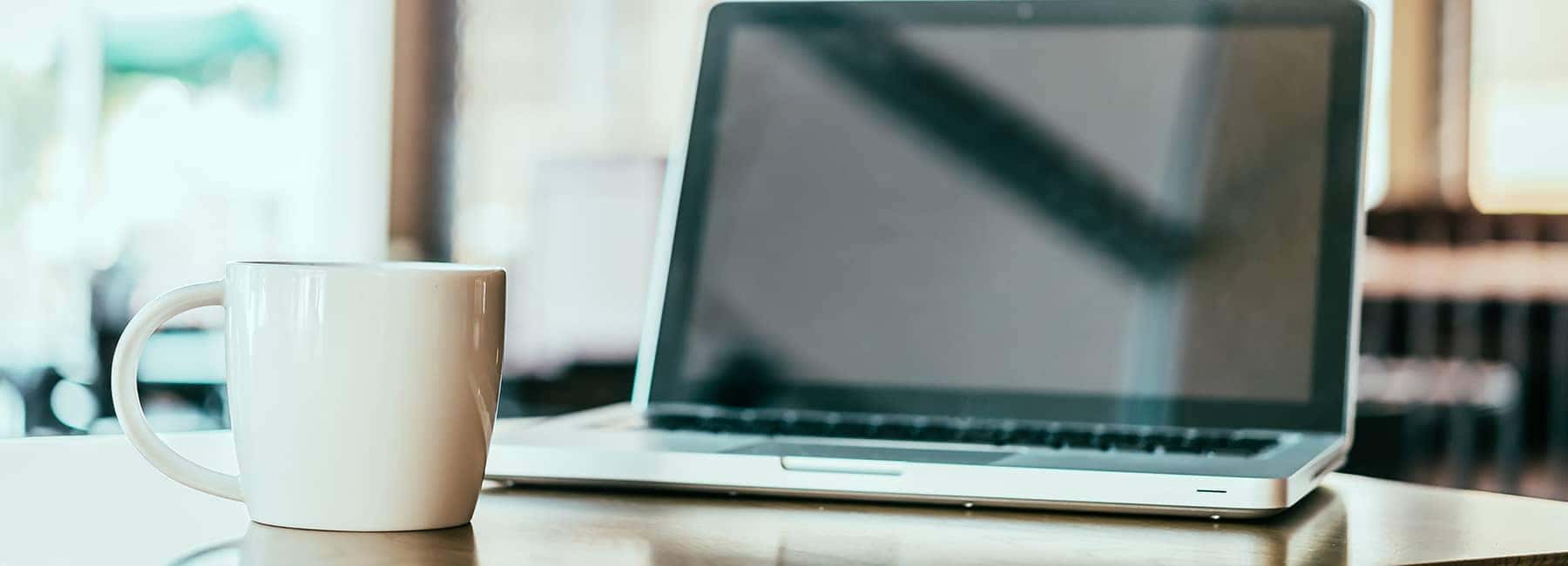 someones laptop by a coffee mug