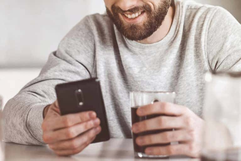 person on cell phone with drink