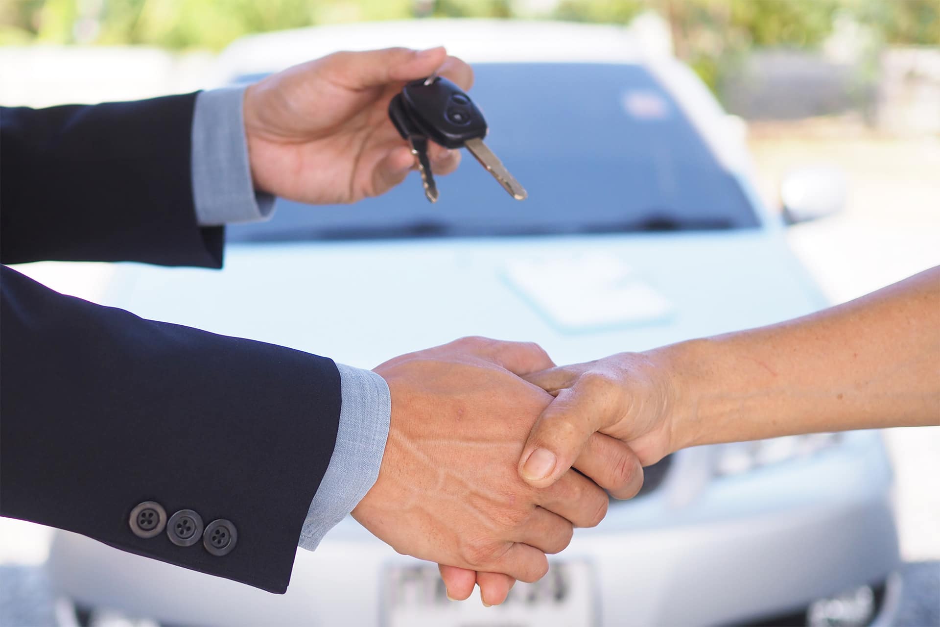 Car salesmen shake hands with new car buyer