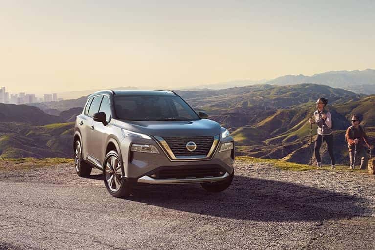 A 2021 Nissan Rogue parked on a mountain top with a city skyline in the valley_mobile