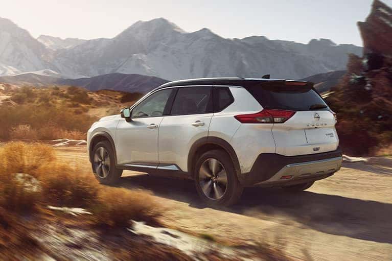 A 2021 White Nissan Rogue driving on a mountain pass_mobile