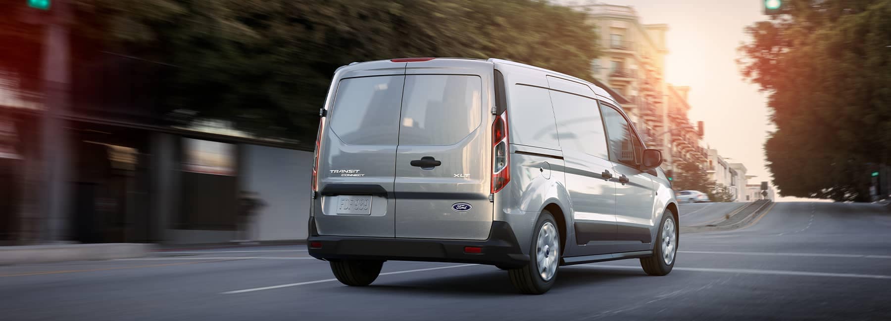 White 2021 Ford Transit driving away on a suburban street