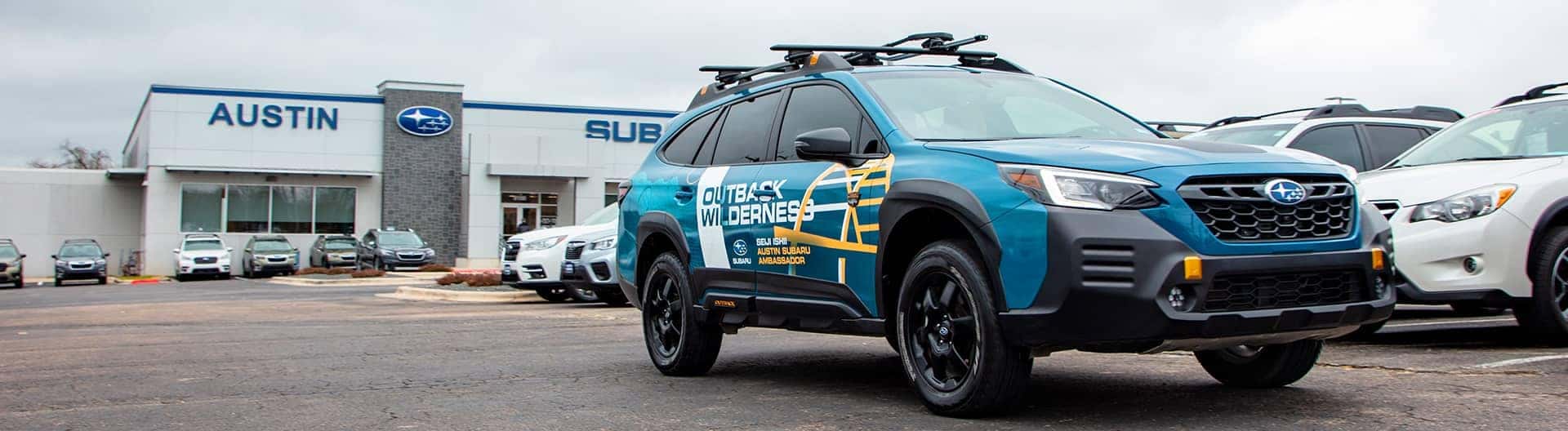 Austin Subaru dealership view from the outside with a Subaru Outback parked in front