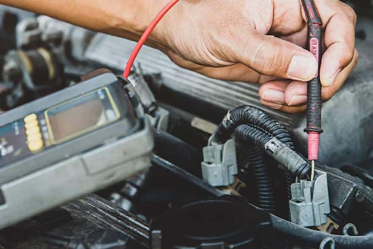 Auto mechanic using measuring equipment tool for fix checking car battery. Concepts of Old car repair service and insurance