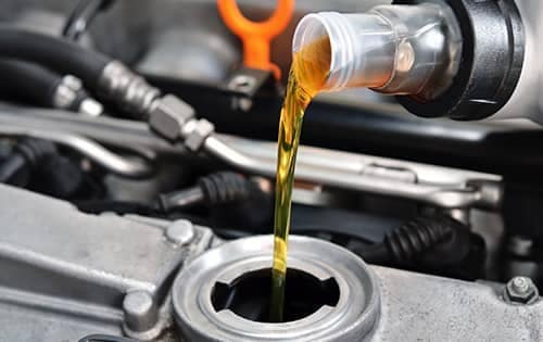 mechanic adds oil to engine