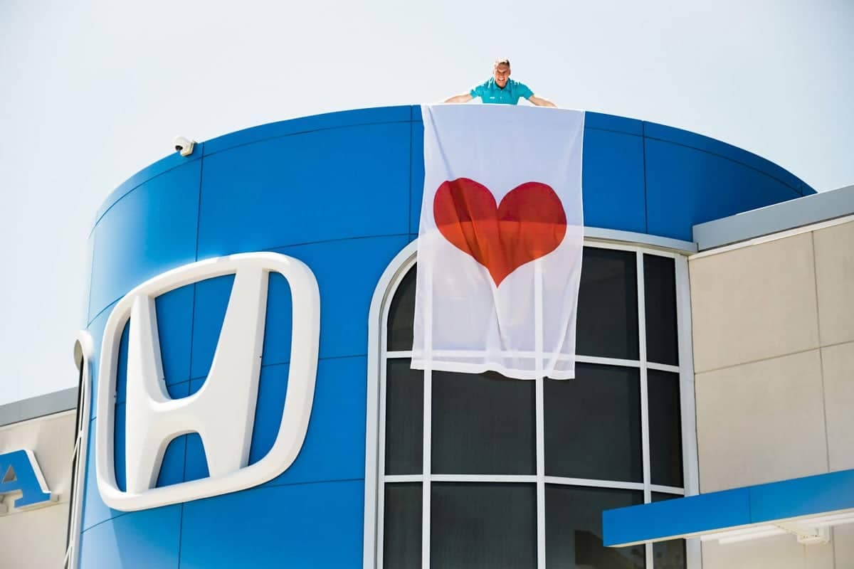 man holds heart flag on rooftop of dealership