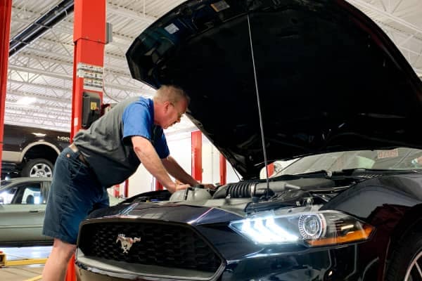Bill Brown Ford Service Center Technician looking under the hood of a Ford Mustang in Michigan 