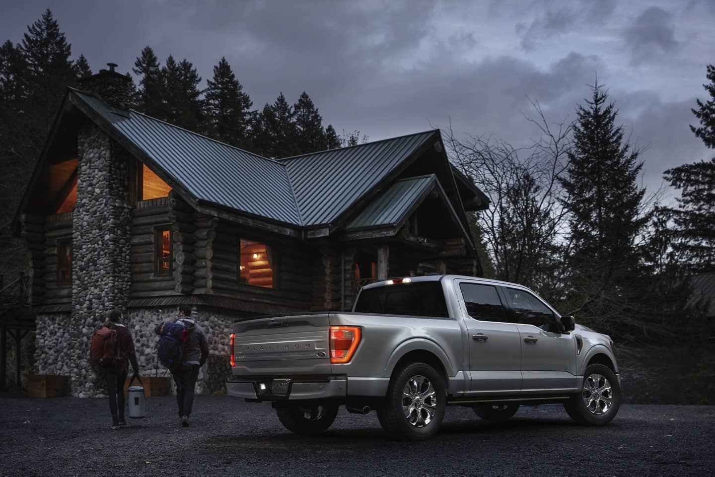 All-new F-150 Platinum in silver parked outside of a log cabin.