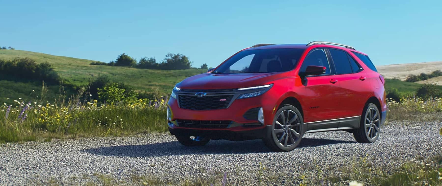 2023 Red Chevrolet Equinox parked on a gravel road in a field