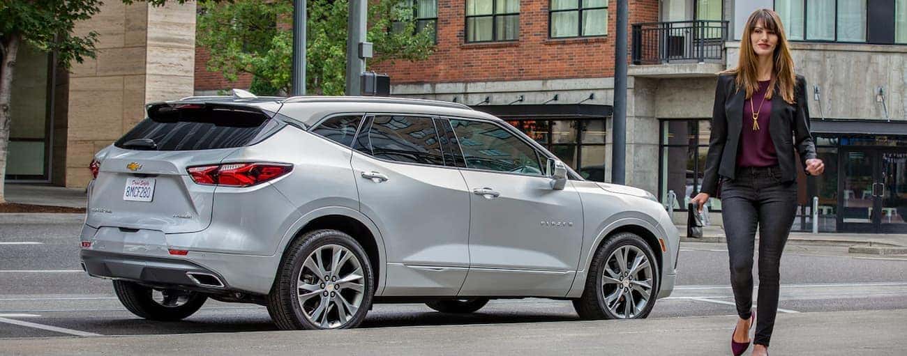 A woman is walking away from a silver 2019 Chevy Blazer on a city street in Indianapolis, IN.