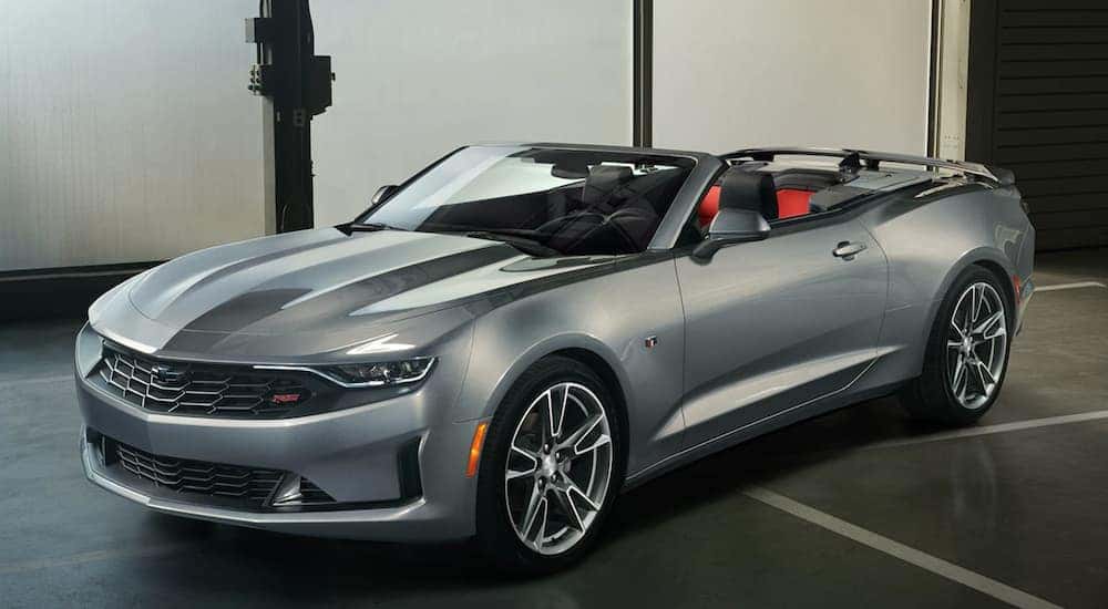A silver 2020 Chevy Camaro is parked in a dark showroom at a Lawrence Chevrolet dealership.