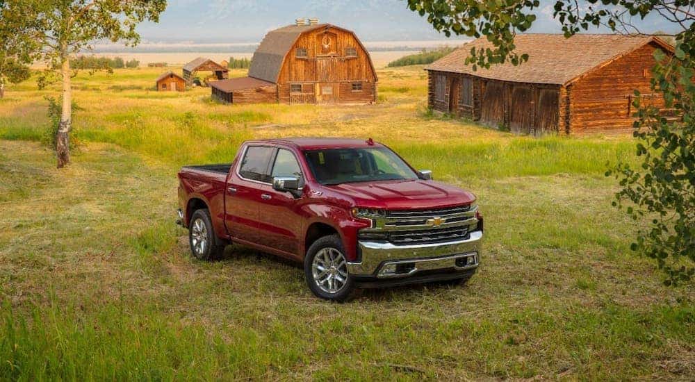 A red 2020 Chevy Silverado 1500 LTZ is parked in front of a farm, a great contender in the 2020 Chevy Silverado 1500 vs 2020 Chevy Silverado 2500HD comparison.