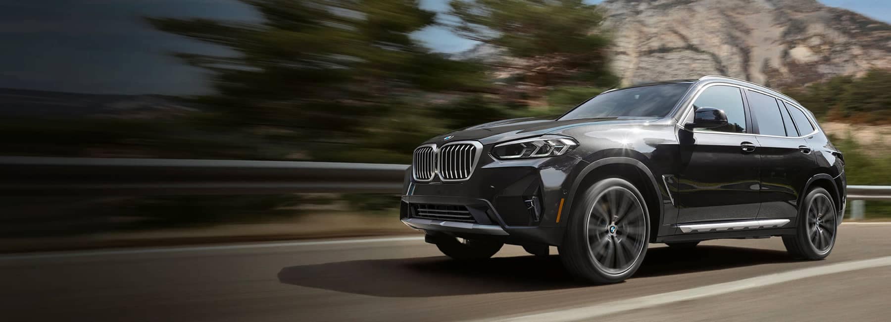 Black 2023 BMW X3 driving on a highway