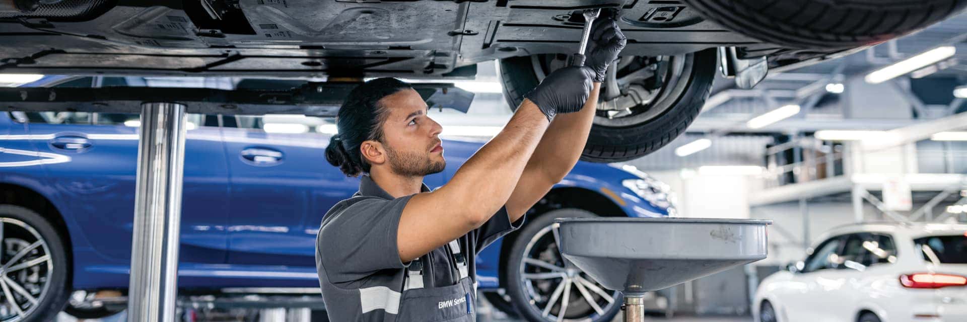 BMW Service Technician working on the underside of a vehicle