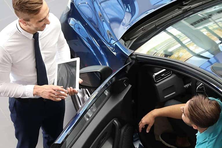 Car salesman reviews car details with a male customer