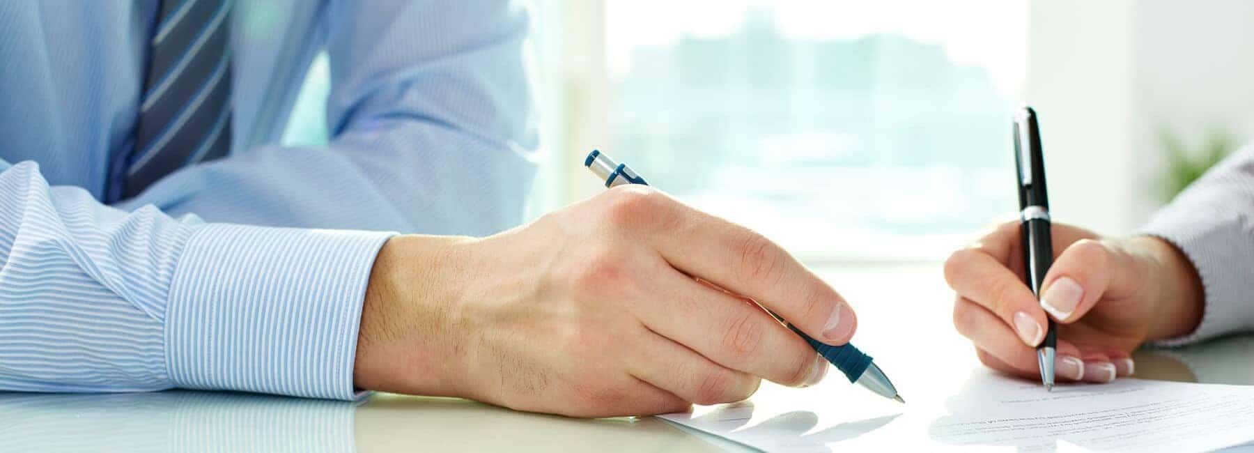 Two Hands Holding Pens Signing a Document2