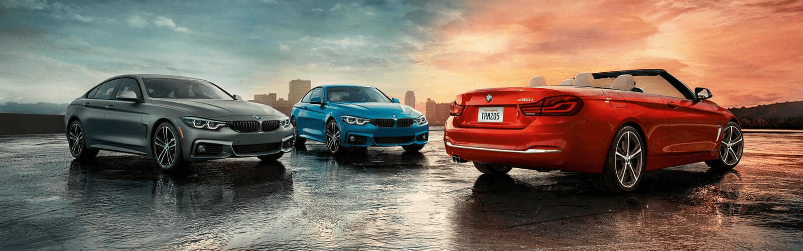 three beautiful BMWs with sun setting behind