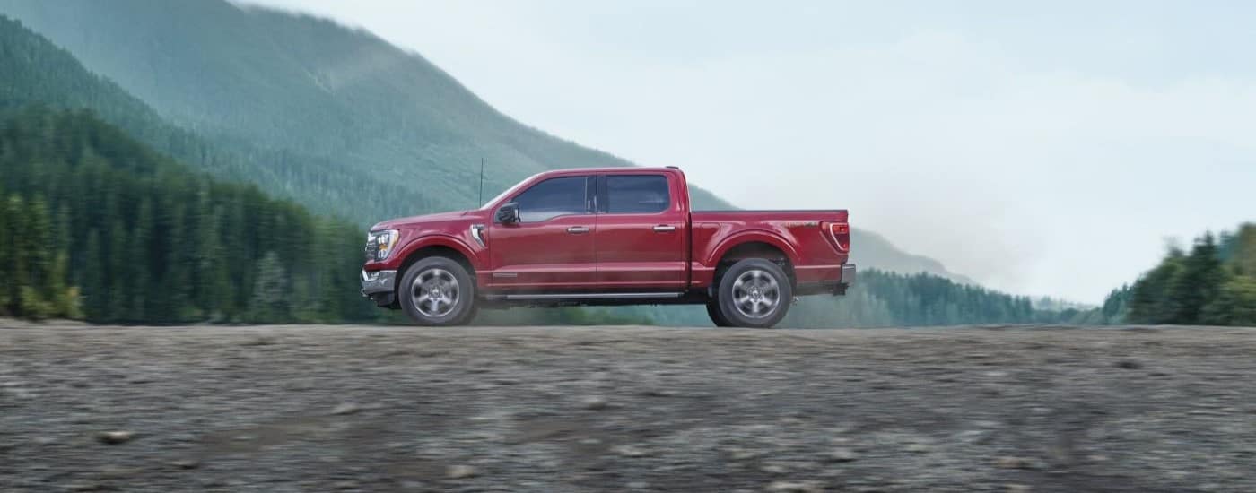 A red 2023 Ford F-150 FX4 is shown from the side driving off-road.