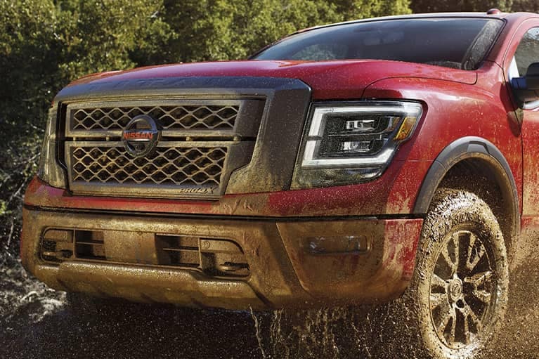 A 2021 Red Nissan Titan truck off roading in dirt
