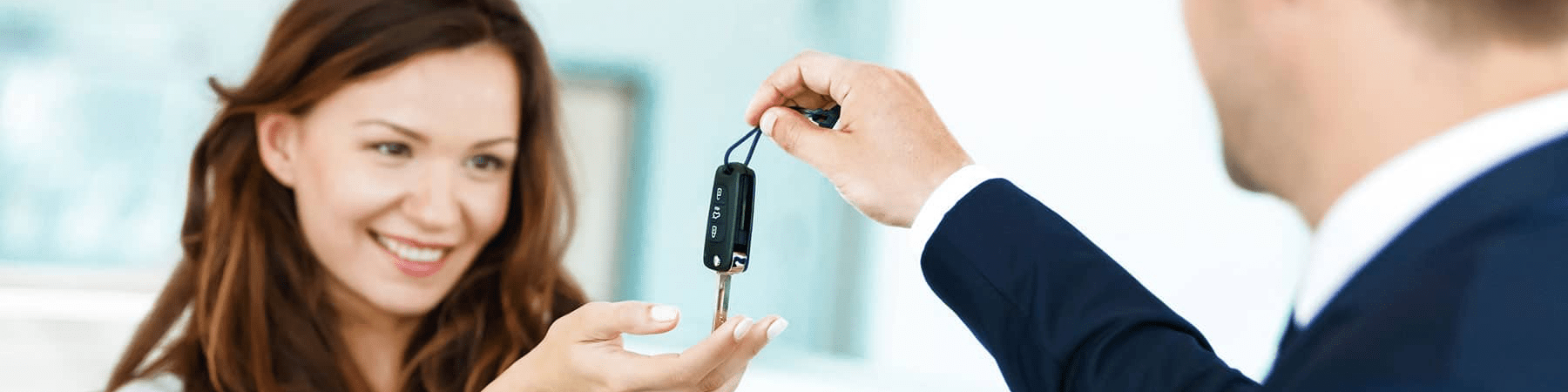 happy woman receives car keys from car dealer