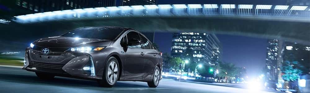2018 Toyota Prius Prime driving city streets at night, part of the Toyota Hybrid model lineup
