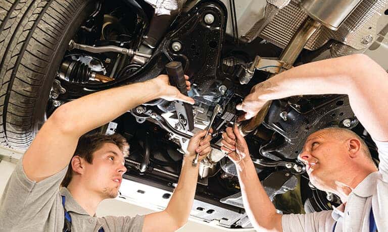 Two mechanics working under a car