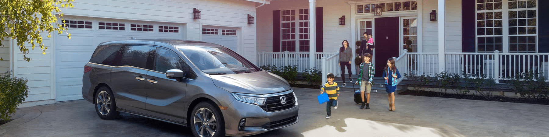 2021 Silver Honda Odyssey parked in front of a white home with black shutters