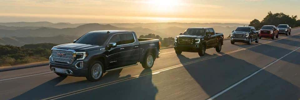 GMC Sierra Trucks driving on a road at sunset