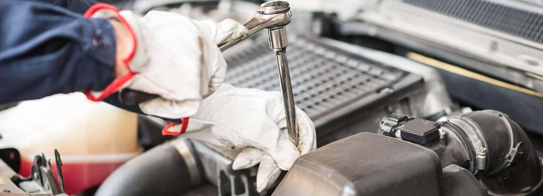 Mechanic Wearing Gloves with Tools working on engine