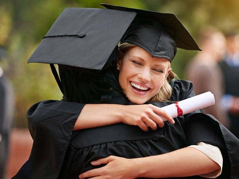 two college graduates embracing
