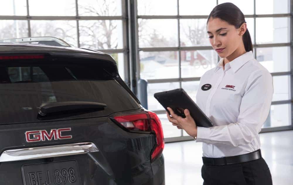 GMC Certified Service Female technician with tablet inspects vehicle exterior