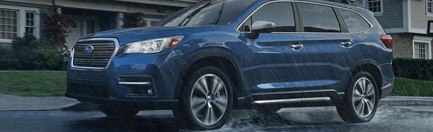 blue Subaru SUV drives in rain