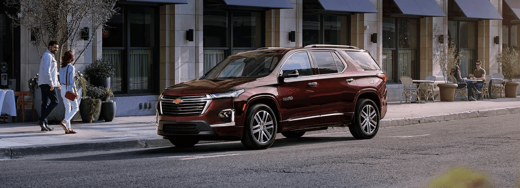 2023-Chevy-Traverse-parked-while-couple-walks-past-city-street