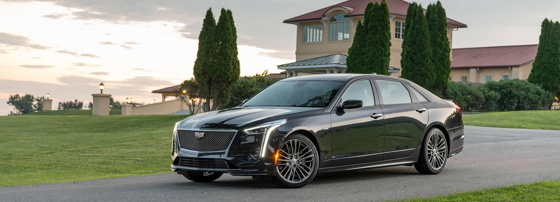 A Black 2019 Cadillac Sedan parked in front of a large building with nice grass