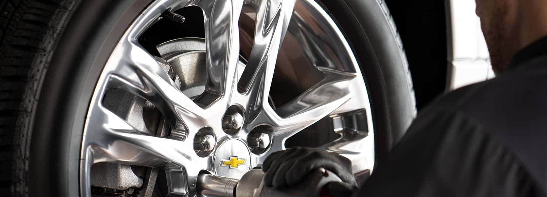 service technician tightens bolts on Chevy wheel
