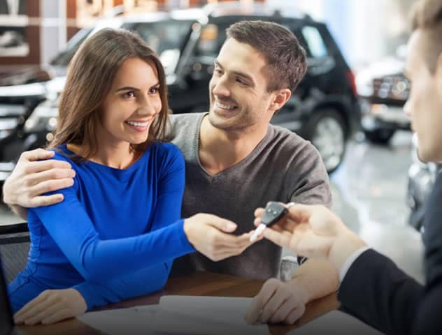 A couple receiving car keys from a sales rep.