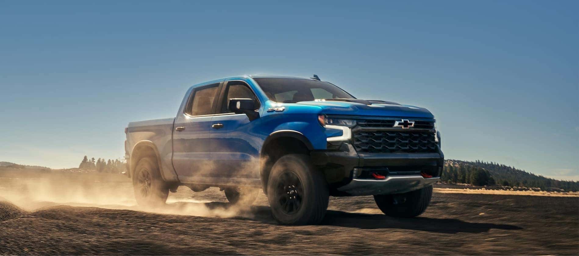 Blue Chevrolet Silverado 1500 parked on dusty dirt