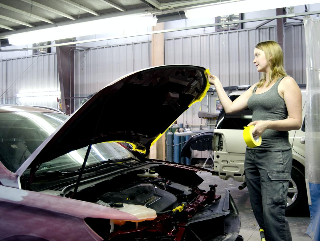 female technician tapes car hood