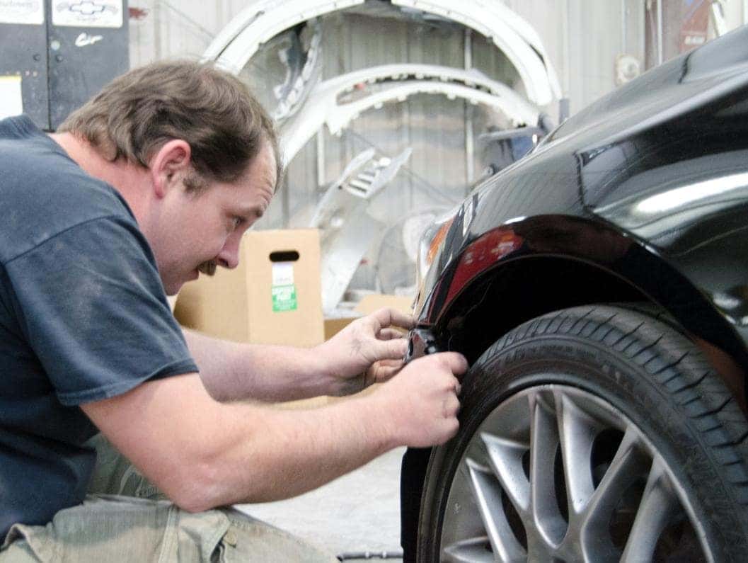 man repairs edge of front bumper